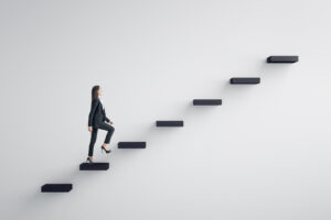 Side view of young businesswoman climbing stairs on concrete wall background. 